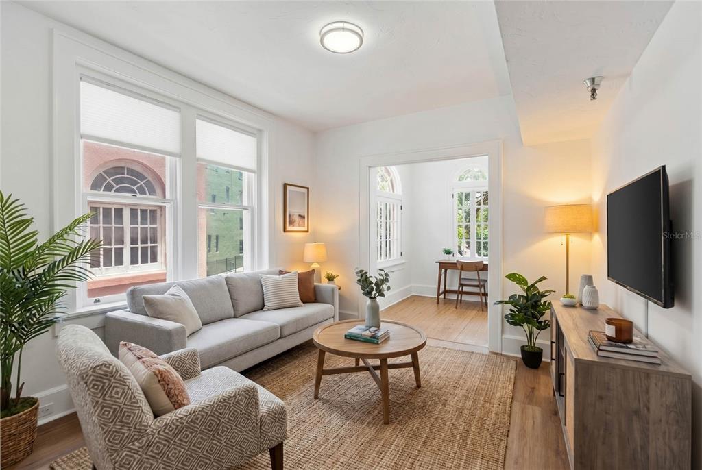 A living room with a grey sofa, patterned armchair, coffee table, and an adjacent office — 1221 N PALM AVENUE UNIT 202, SARASOTA, FL