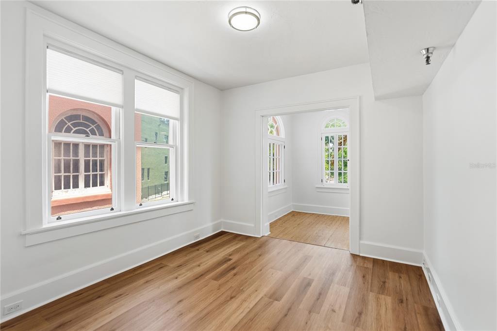 A bright room with wood-look flooring and a doorway leading to an adjacent sunroom — 1221 N PALM AVENUE UNIT 202, SARASOTA, FL
