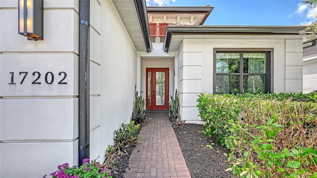 A brick walkway leads to the red front door of a white stucco house — 17202 CRESSWIND TERRACE, BRADENTON, FL