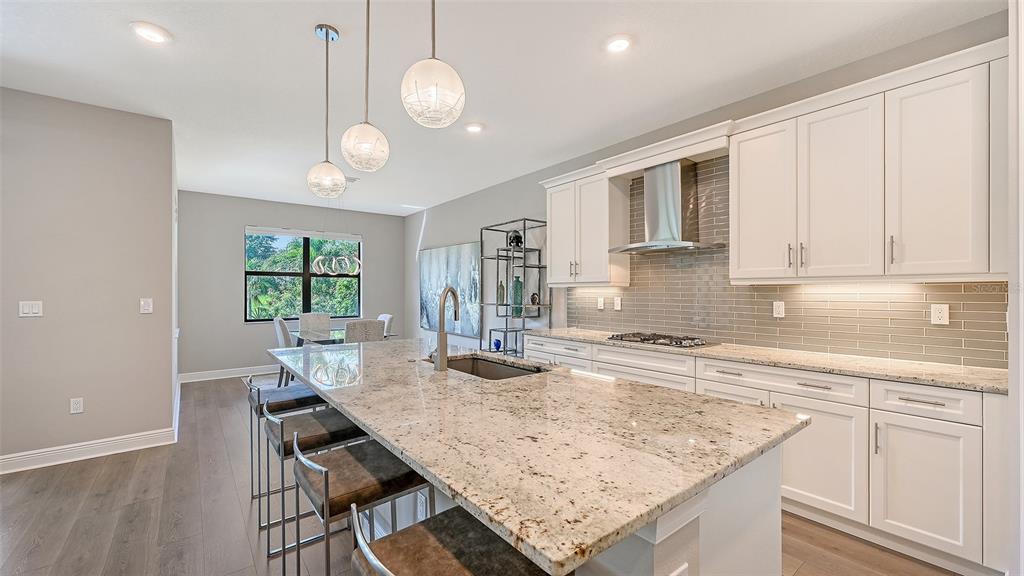 A modern kitchen features white cabinets, granite countertops, a large island, and stainless steel appliances — 17202 CRESSWIND TERRACE, BRADENTON, FL