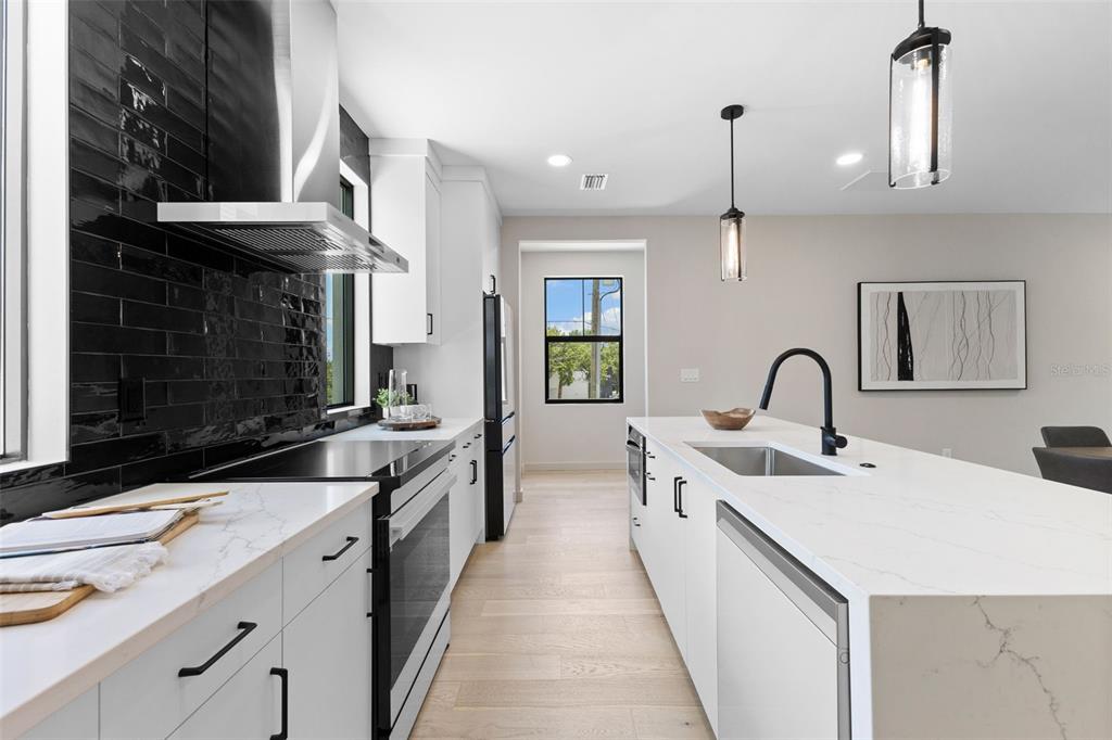 A modern kitchen features white cabinets, quartz countertops, a black tile backsplash, and a center island — 2211 16TH STREET N, ST PETERSBURG, FL