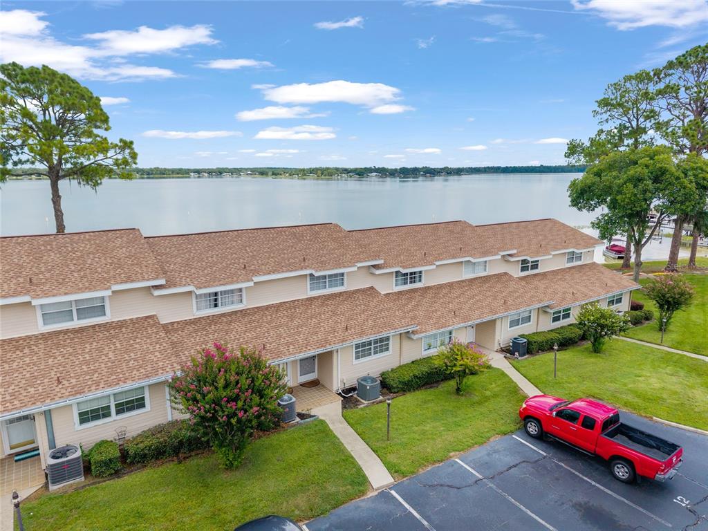 An aerial view of a multi-unit townhouse building with a lake in the background — 11001 SE SUNSET HARBOR ROAD UNIT B13, SUMMERFIELD, FL