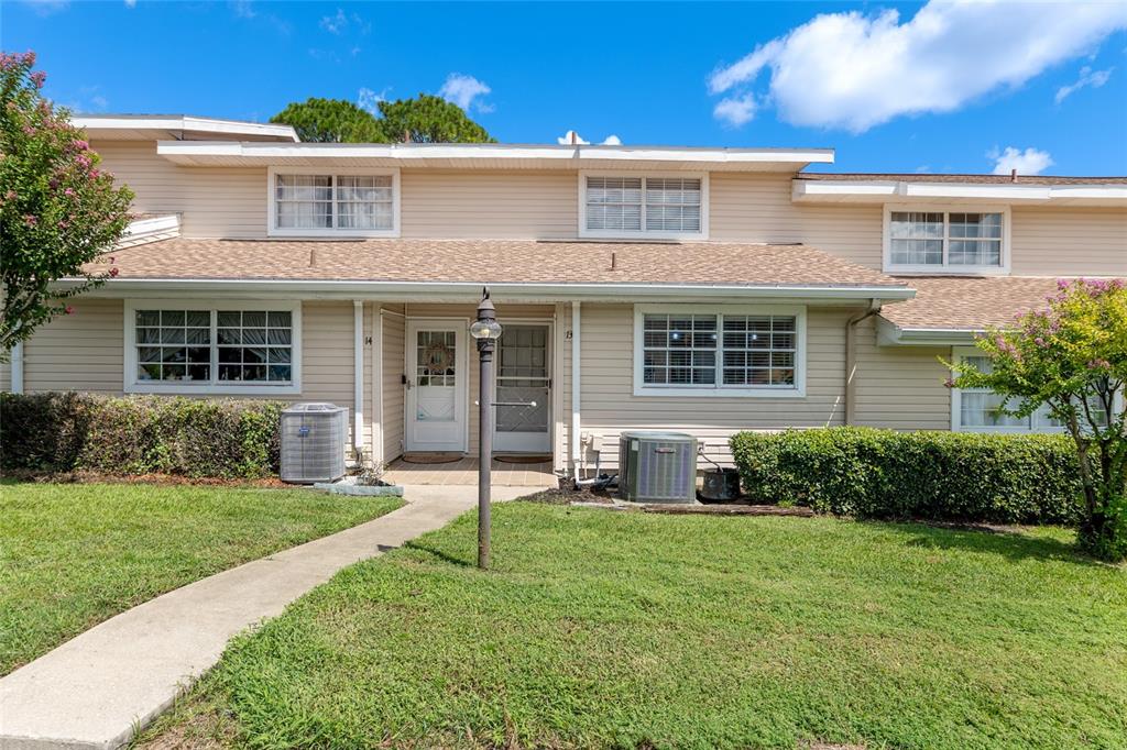 The exterior of a two-story townhouse features beige siding, two front doors, and a lawn — 11001 SE SUNSET HARBOR ROAD UNIT B13, SUMMERFIELD, FL