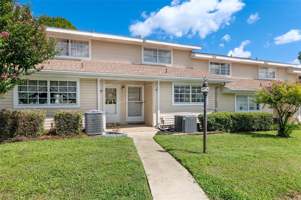 A two-story townhouse exterior with beige siding, a concrete walkway, and two air conditioning units — 11001 SE SUNSET HARBOR ROAD UNIT B13, SUMMERFIELD, FL