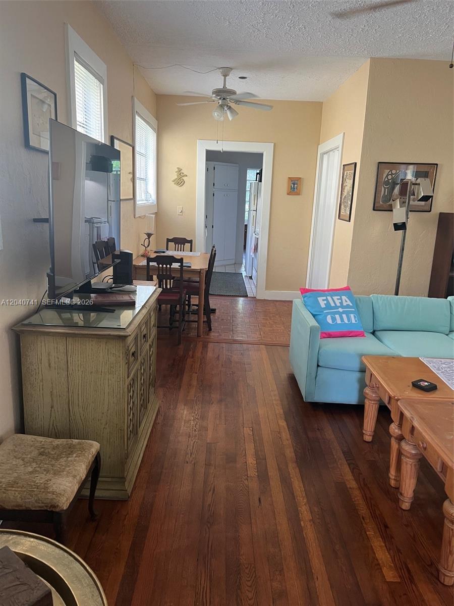 A living room with hardwood floors, a light blue sofa, and a dining area beyond — 1209 Aguila Ave, Coral Gables FL 33134, CORAL GABLES, FL