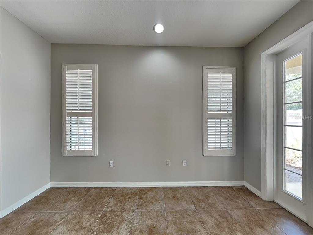 A room with light gray walls, tile flooring, two shuttered windows, and a glass door — 33314 PORTAL DRIVE, LEESBURG, FL