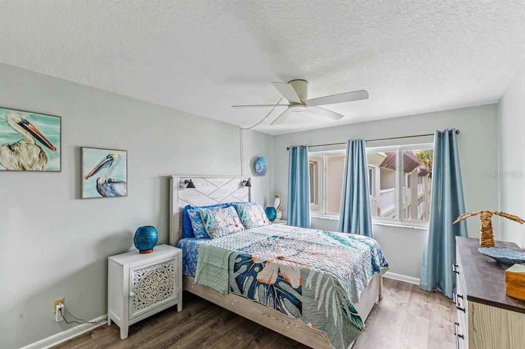 A bedroom features a bed with tropical bedding, light blue walls, and a ceiling fan — 3663 S ATLANTIC AVENUE UNIT 33B, NEW SMYRNA BEACH, FL