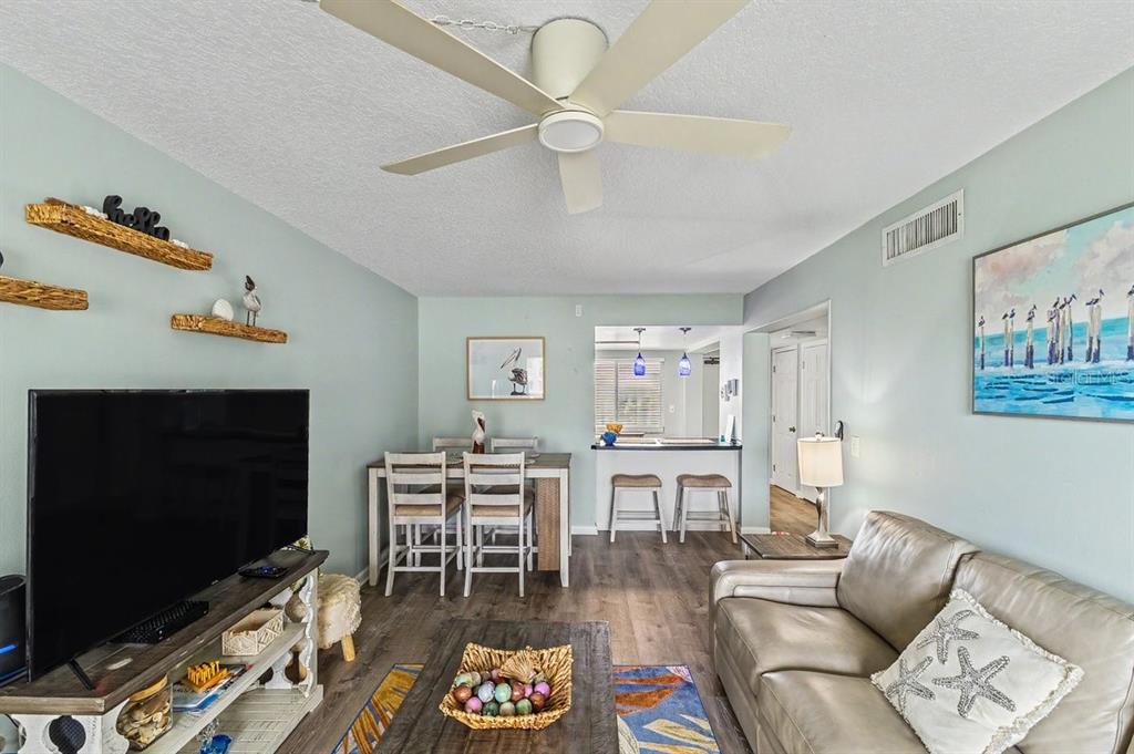 A living room and dining area with light blue walls, wood-look flooring, and a ceiling fan — 3663 S ATLANTIC AVENUE UNIT 33B, NEW SMYRNA BEACH, FL