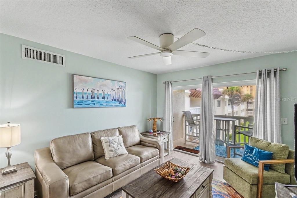 A living room features a beige sofa, green armchair, wooden coffee table, and sliding glass doors — 3663 S ATLANTIC AVENUE UNIT 33B, NEW SMYRNA BEACH, FL