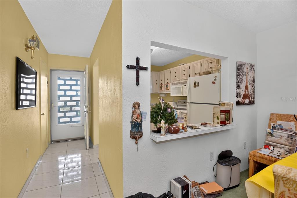 A view of a home entryway with yellow walls, tile flooring, and a kitchen pass-through window — 2711 N HALIFAX AVENUE UNIT 693, DAYTONA BEACH, FL