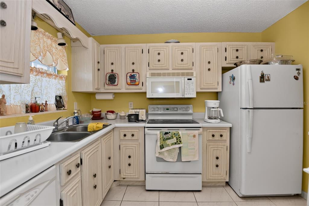 A kitchen features white cabinets, yellow walls, a white stove, and a white refrigerator — 2711 N HALIFAX AVENUE UNIT 693, DAYTONA BEACH, FL