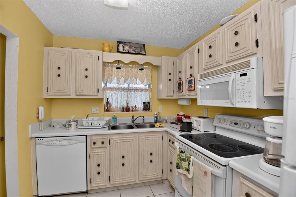 A kitchen with yellow walls, white cabinets, a white dishwasher, and a black stovetop — 2711 N HALIFAX AVENUE UNIT 693, DAYTONA BEACH, FL