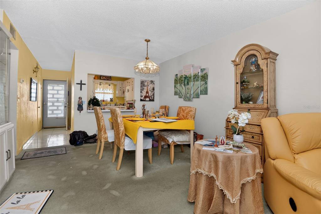 A dining room features a yellow-clothed table, a hutch, and a pass-through to the kitchen — 2711 N HALIFAX AVENUE UNIT 693, DAYTONA BEACH, FL