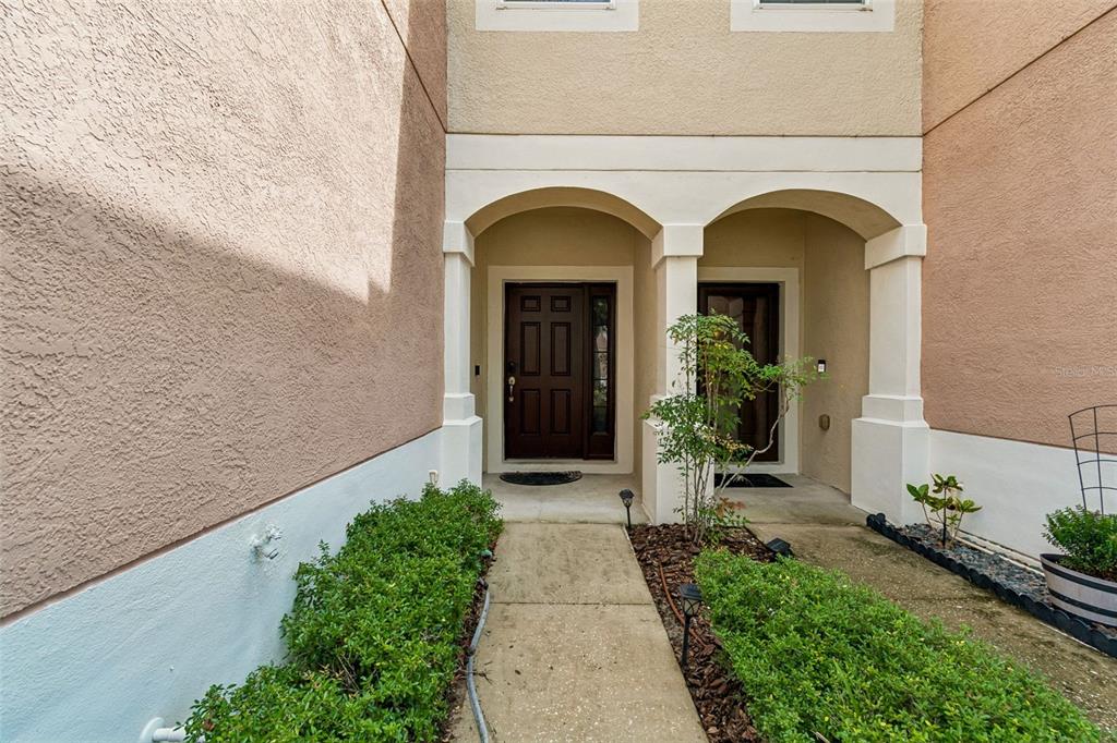 A bedroom features a gray upholstered bed, two nightstands, a large window, and a potted plant — 26523 CHIMNEY SPIRE LANE, WESLEY CHAPEL, FL