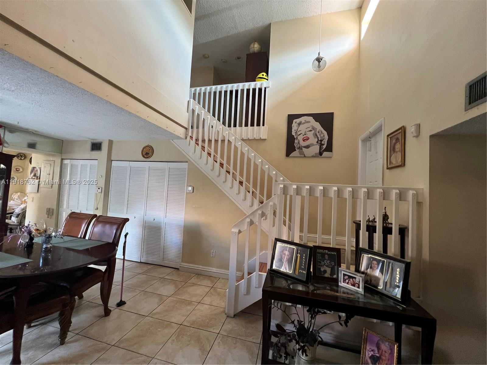 A dining area features a staircase with white railings and a high vaulted ceiling — 4900 SW 149th Ct # 12C, Miami FL 33185, MIAMI, FL