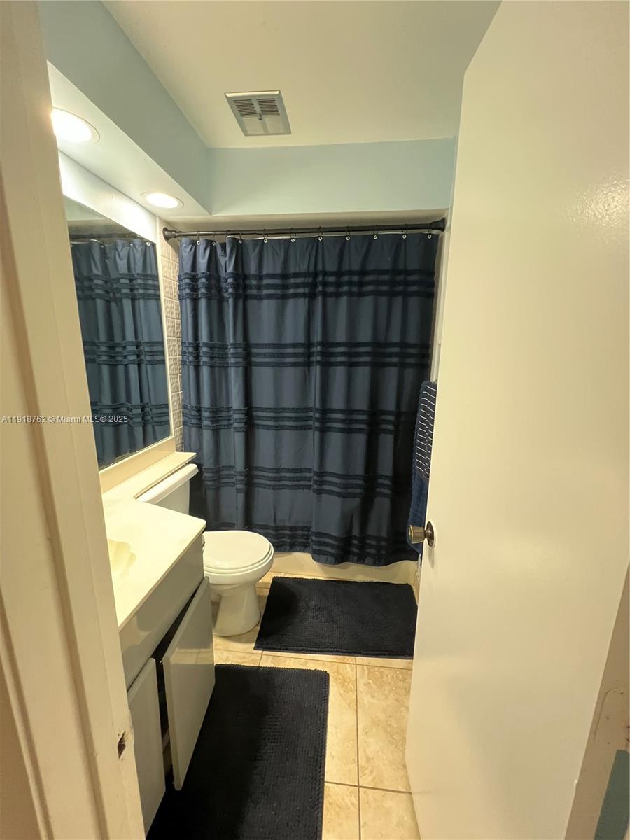 A bathroom features a vanity, a toilet, and a shower with a dark blue curtain — 4900 SW 149th Ct # 12C, Miami FL 33185, MIAMI, FL