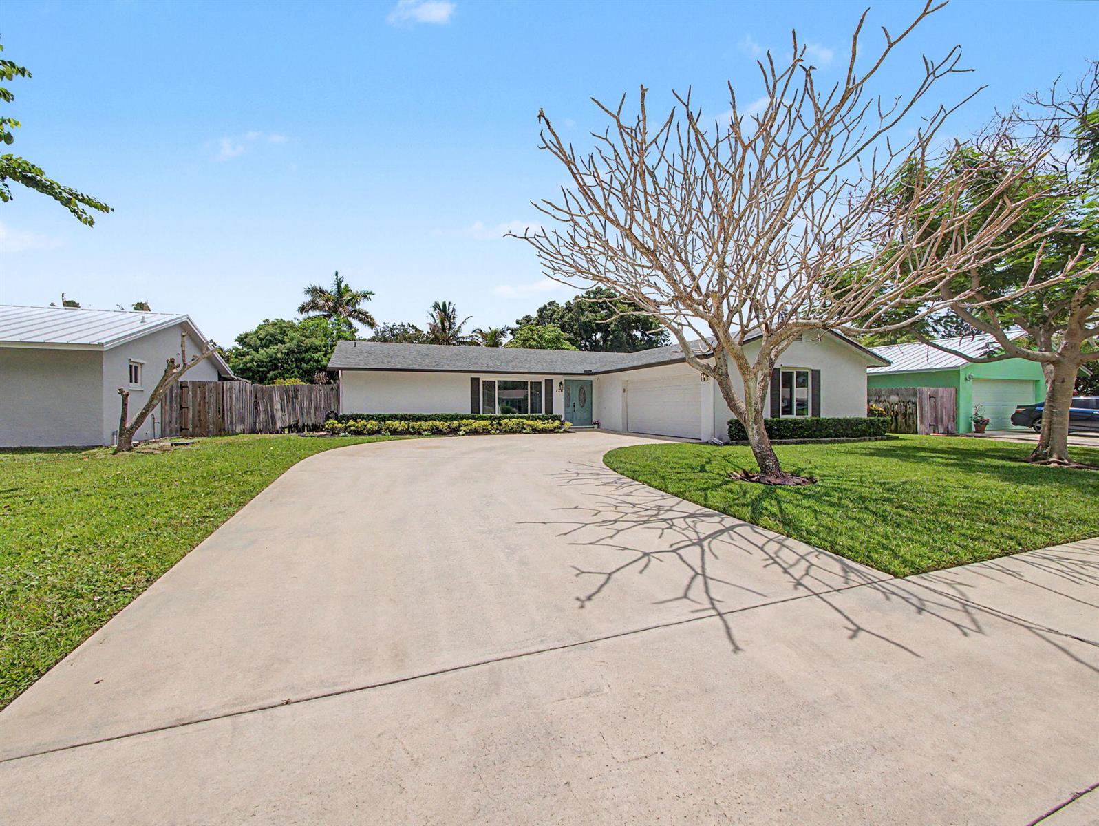 A single-story house with a white exterior, a concrete driveway, and a large bare tree — 126 Chapel Lane, Tequesta FL 33469, TEQUESTA, FL