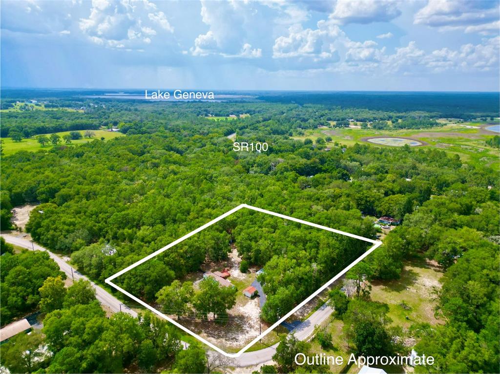 An aerial view shows a wooded residential lot outlined in white near a road — 8232 SWAN LAKE ROAD, MELROSE, FL