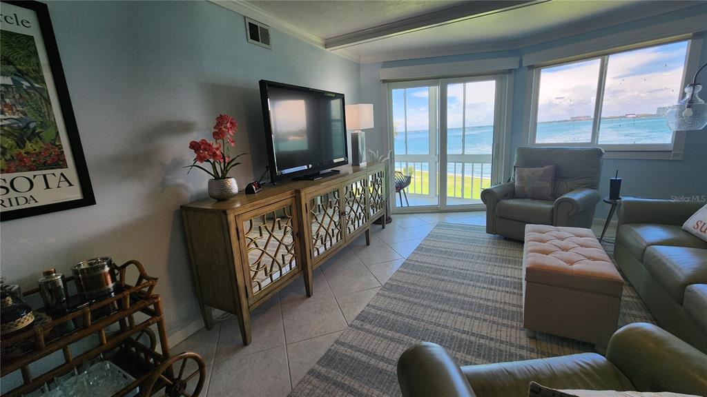 A three-story white apartment building features a covered parking area with several parked cars — 777 JOHN RINGLING BOULEVARD UNIT 24, SARASOTA, FL