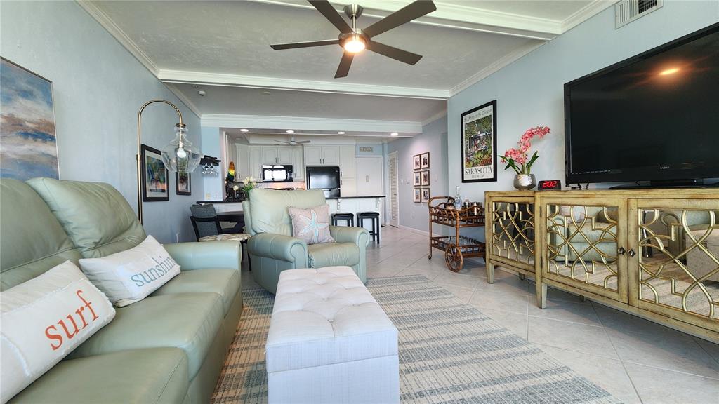 A kitchen with white cabinets and granite countertops opens into a living area with water views — 777 JOHN RINGLING BOULEVARD UNIT 24, SARASOTA, FL