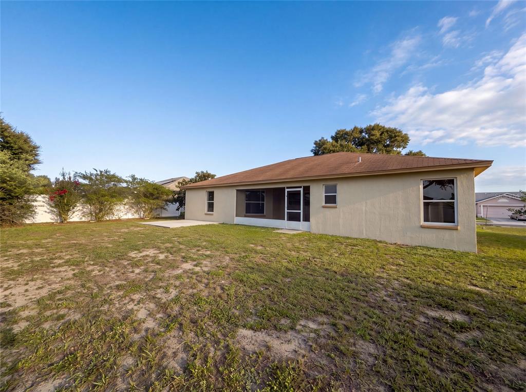 The exterior rear view of a single-story house features a screened-in porch and yard — 1038 HIGHLAND CREST CIRCLE, LAKE WALES, FL