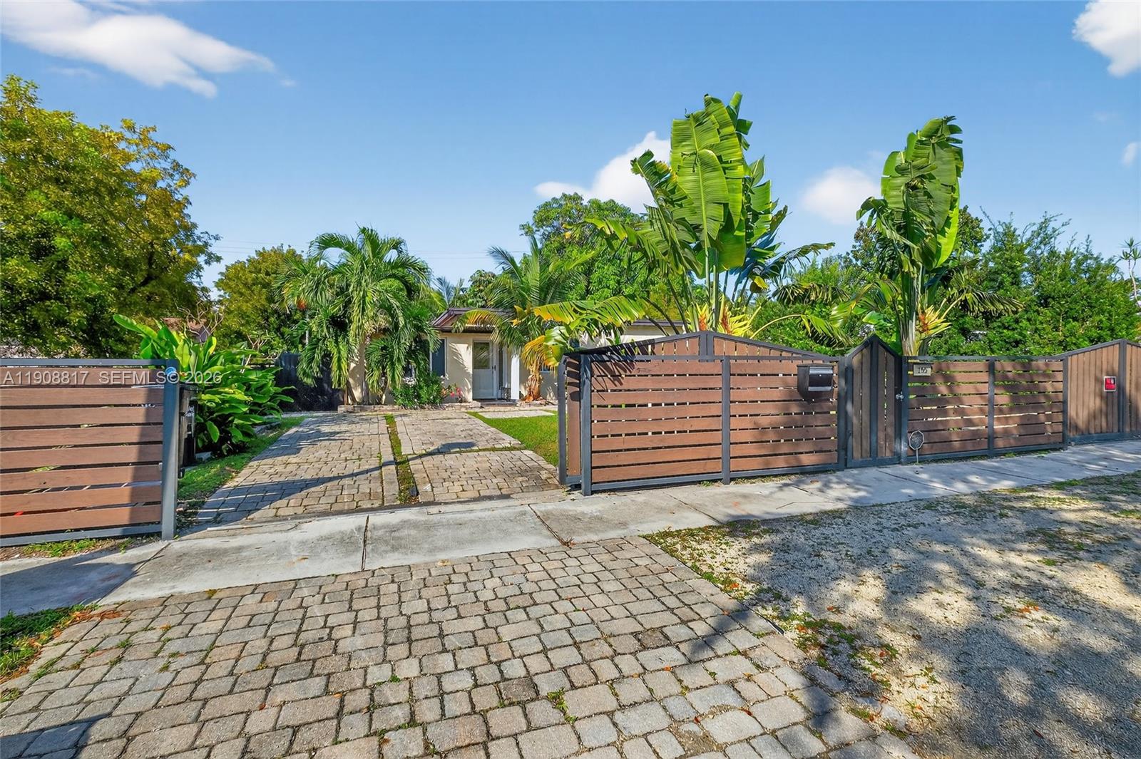 A paved driveway leads to a house behind a modern horizontal wood privacy fence — 155 NW 124th St, North Miami FL 33168, NORTH MIAMI, FL