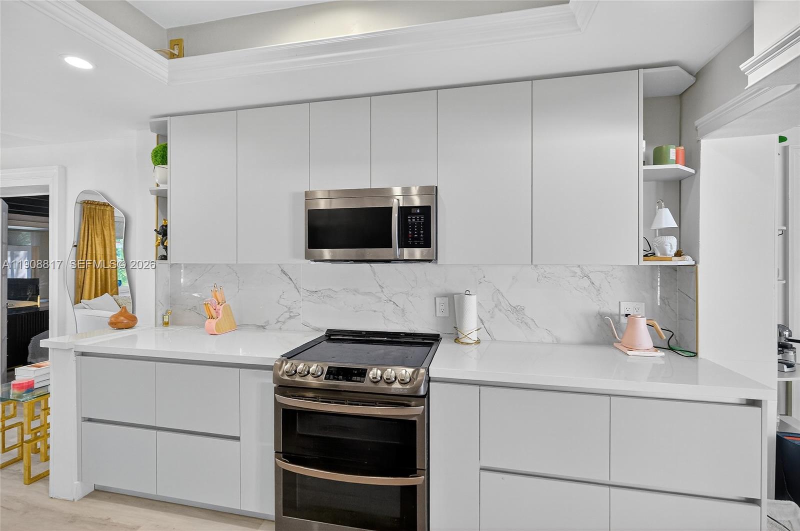 A modern kitchen features white flat-panel cabinetry, a marble backsplash, and stainless steel appliances — 155 NW 124th St, North Miami FL 33168, NORTH MIAMI, FL