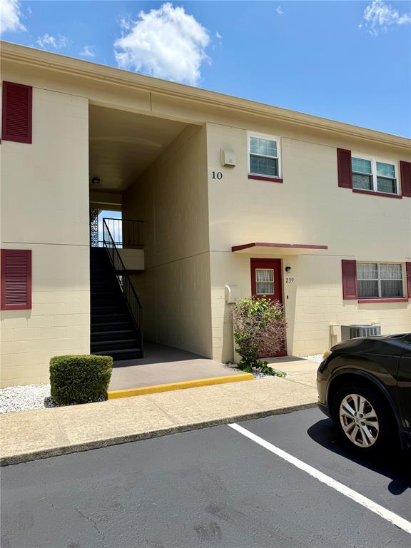 An exterior view of a two-story apartment building with beige walls and red shutters — 5505 HERNANDES DRIVE UNIT 239, ORLANDO, FL