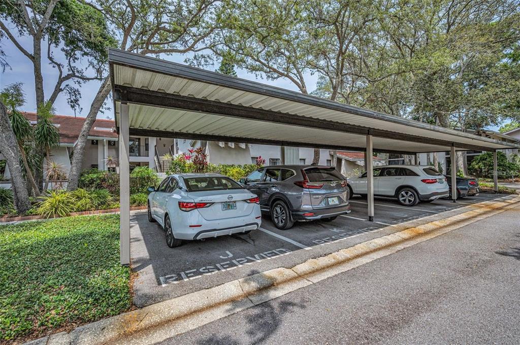 A covered parking area with three vehicles parked in marked reserved spaces — 300 S FLORIDA AVENUE UNIT 200J, TARPON SPRINGS, FL