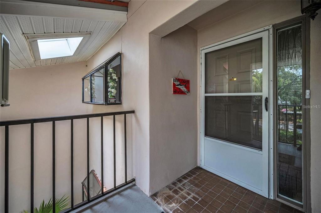 An exterior entryway features a tiled floor, a screen door, and a black metal railing — 300 S FLORIDA AVENUE UNIT 200J, TARPON SPRINGS, FL