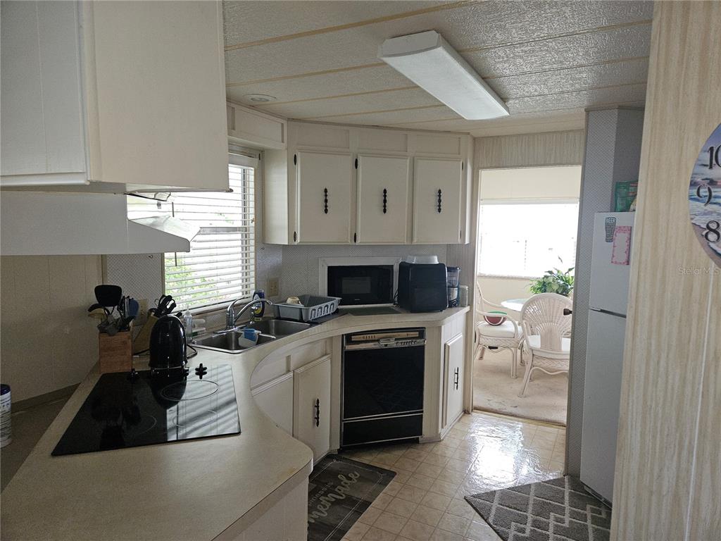 A kitchen features white cabinets, a black cooktop, a built-in oven, and a double sink — 26087 COUNTESS LANE, BONITA SPRINGS, FL