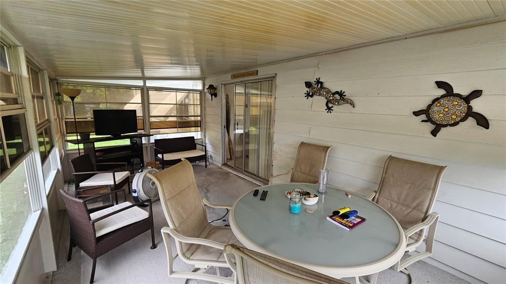 A screened-in porch features a dining set, lounge chairs, a television, and wall-mounted decorations — 26087 COUNTESS LANE, BONITA SPRINGS, FL