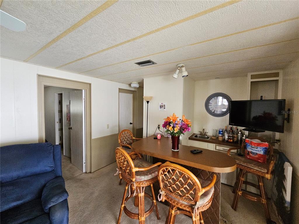 A room features a bar with wicker stools, a television, and a blue armchair — 26087 COUNTESS LANE, BONITA SPRINGS, FL