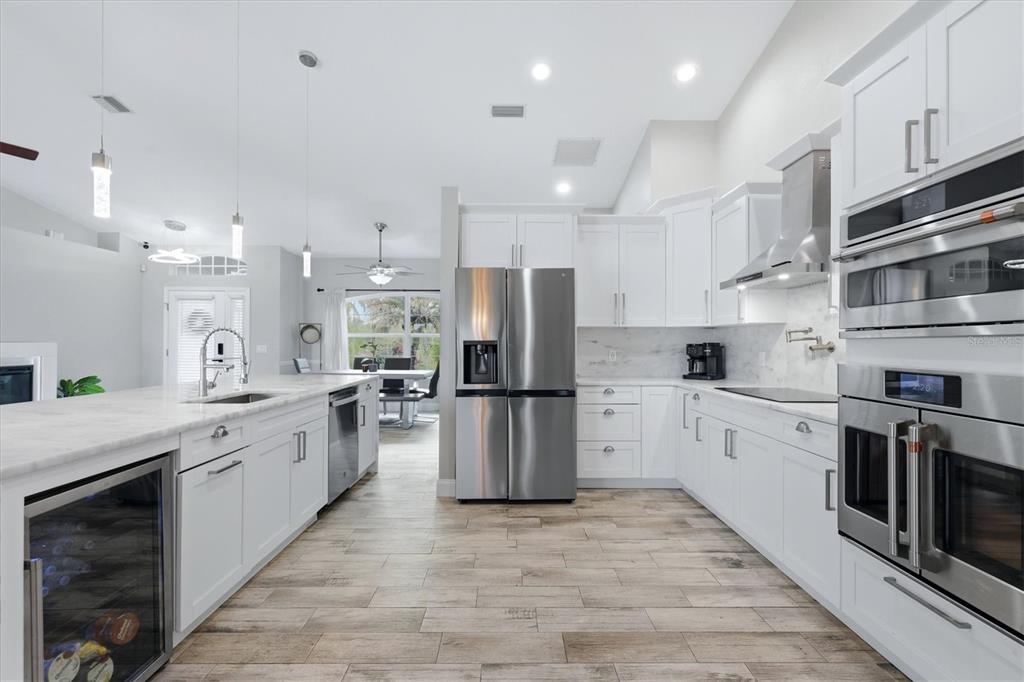 A modern kitchen features white cabinetry, stainless steel appliances, and a marble-topped island — 8188 WELSFORD ROAD, PORT CHARLOTTE, FL