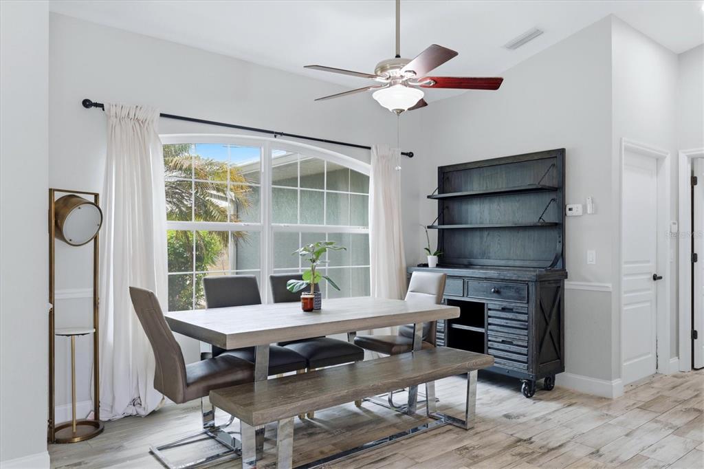 A dining room features a wooden table, chairs, a bench, and a dark hutch — 8188 WELSFORD ROAD, PORT CHARLOTTE, FL