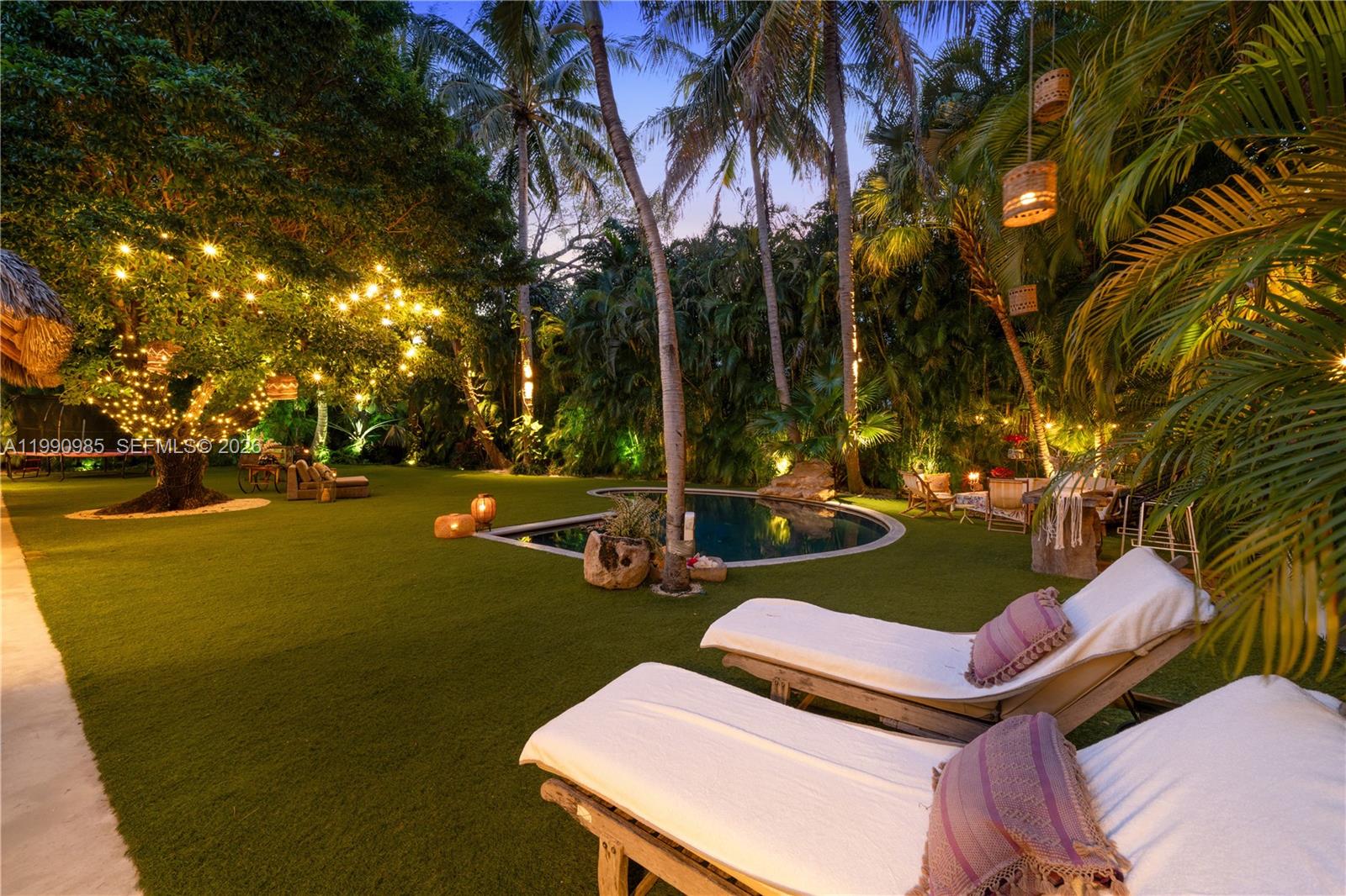A backyard features a swimming pool, lounge chairs, palm trees, and string lights at dusk — 330 Gulf Rd, Key Biscayne FL 33149, KEY BISCAYNE, FL