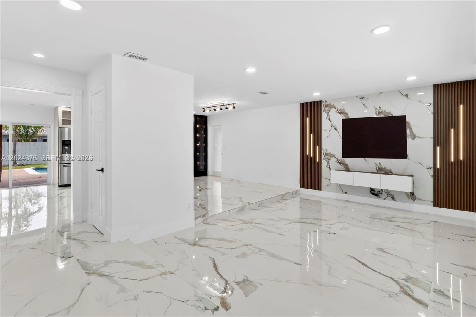 A living room features white marble flooring, a marble accent wall, and recessed lighting — 7220 NW 10th Pl, Plantation FL 33313, PLANTATION, FL