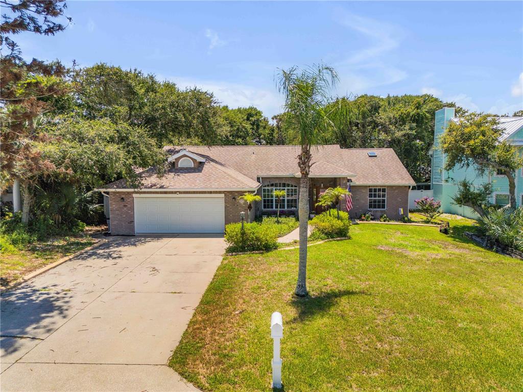 A single-story brick house with a two-car garage, a palm tree, and a concrete driveway — 815 E 7TH AVENUE, NEW SMYRNA BEACH, FL