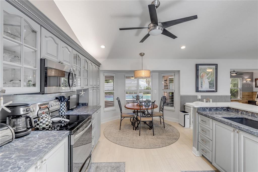 A kitchen with gray cabinets, blue-toned countertops, and a dining area with a round table — 815 E 7TH AVENUE, NEW SMYRNA BEACH, FL