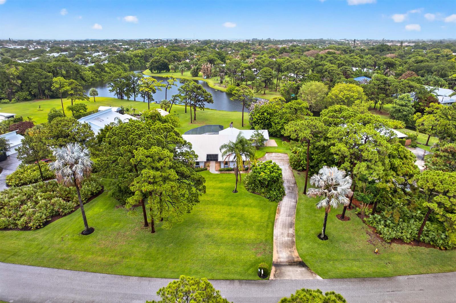 An aerial view shows a house with a white roof, driveway, and pool enclosure — 441 NE Town Terrace, Jensen Beach FL 34957, JENSEN BEACH, FL
