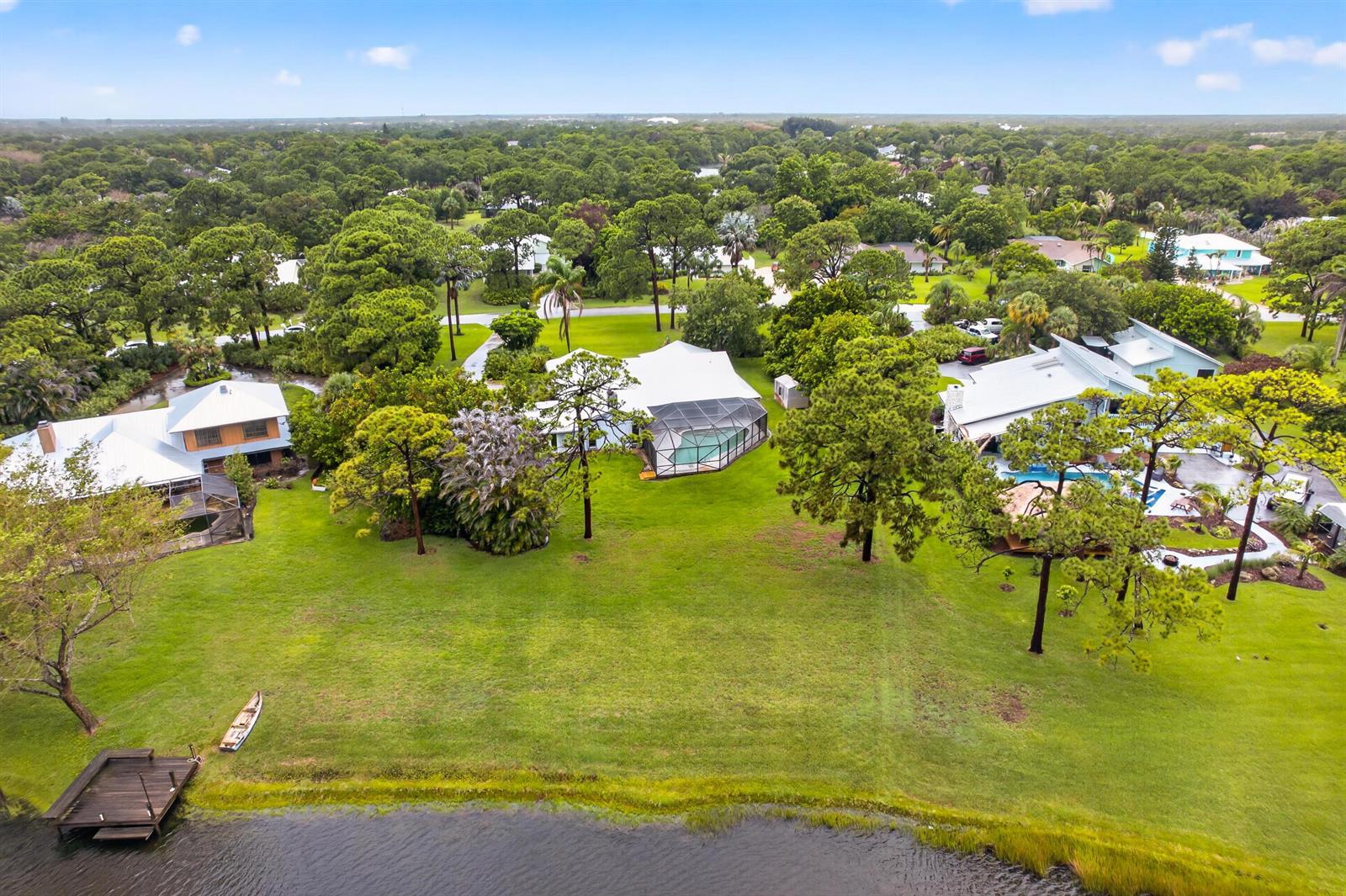 An aerial view shows three houses with pools situated on a large grassy waterfront lot — 441 NE Town Terrace, Jensen Beach FL 34957, JENSEN BEACH, FL