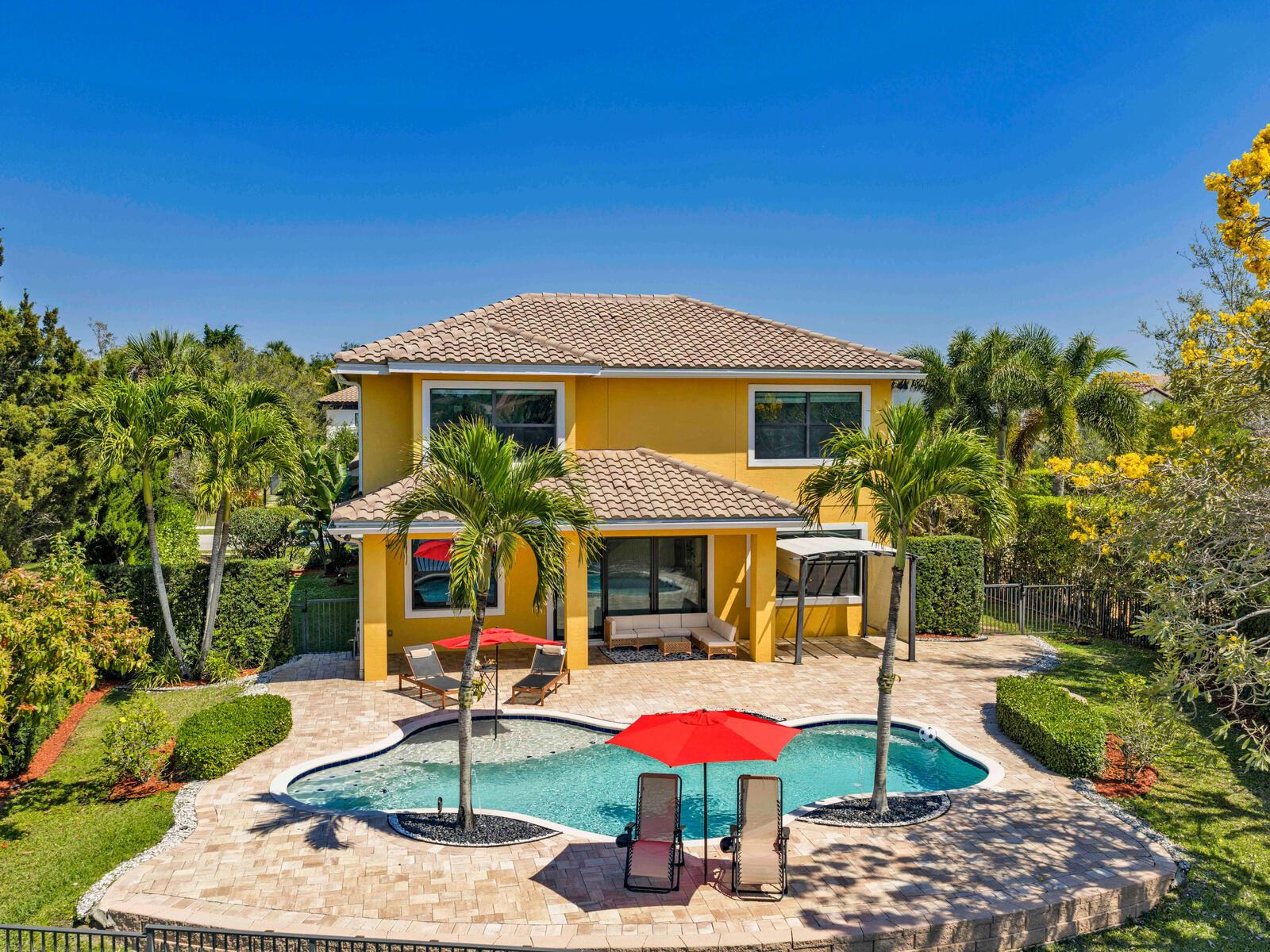 A two-story yellow house features a backyard swimming pool, patio furniture, and palm trees — 8256 Bradford Way, Parkland FL 33076, PARKLAND, FL