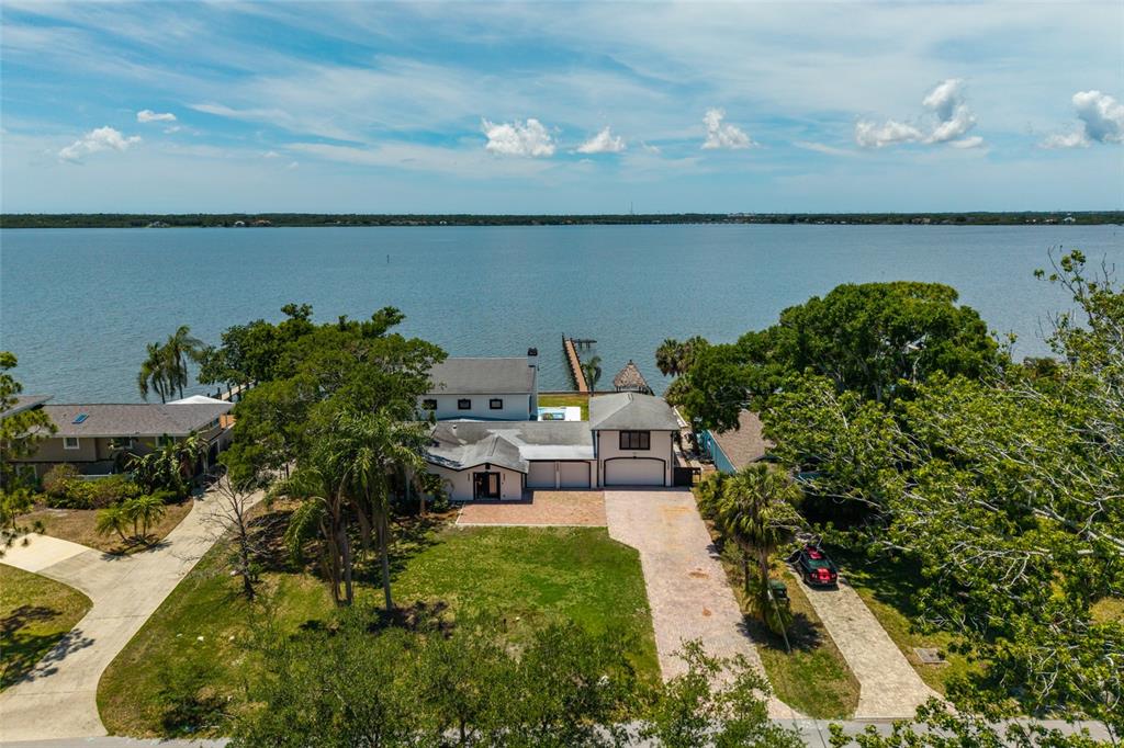 An aerial view shows a waterfront house with a paved driveway and a private dock — 412 SHORE DRIVE E, OLDSMAR, FL