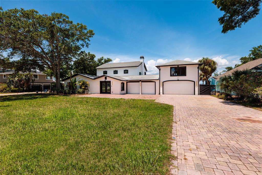A white two-story house with a brick driveway and a large front lawn — 412 SHORE DRIVE E, OLDSMAR, FL