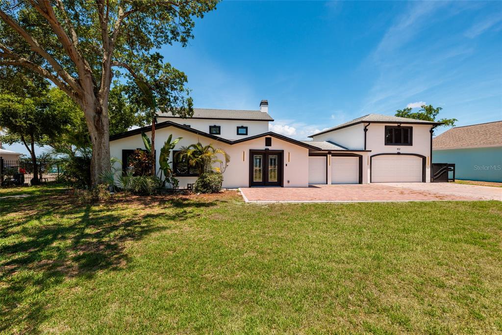 A two-story white house with a brick driveway and a three-car garage — 412 SHORE DRIVE E, OLDSMAR, FL