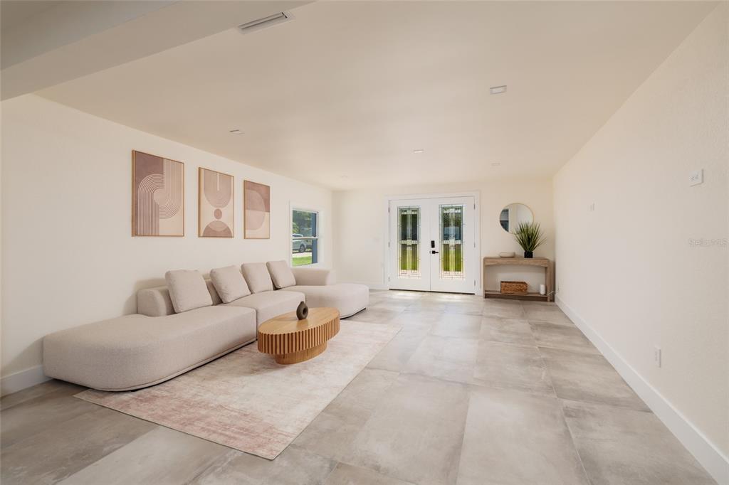 A living room features a large beige sectional, a wooden coffee table, and tile flooring — 412 SHORE DRIVE E, OLDSMAR, FL