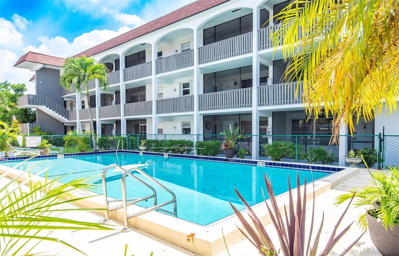 A multi-story apartment building with balconies overlooks a rectangular swimming pool with a metal ladder — 651 Pine Drive # 306, Pompano Beach FL 33060, POMPANO BEACH, FL