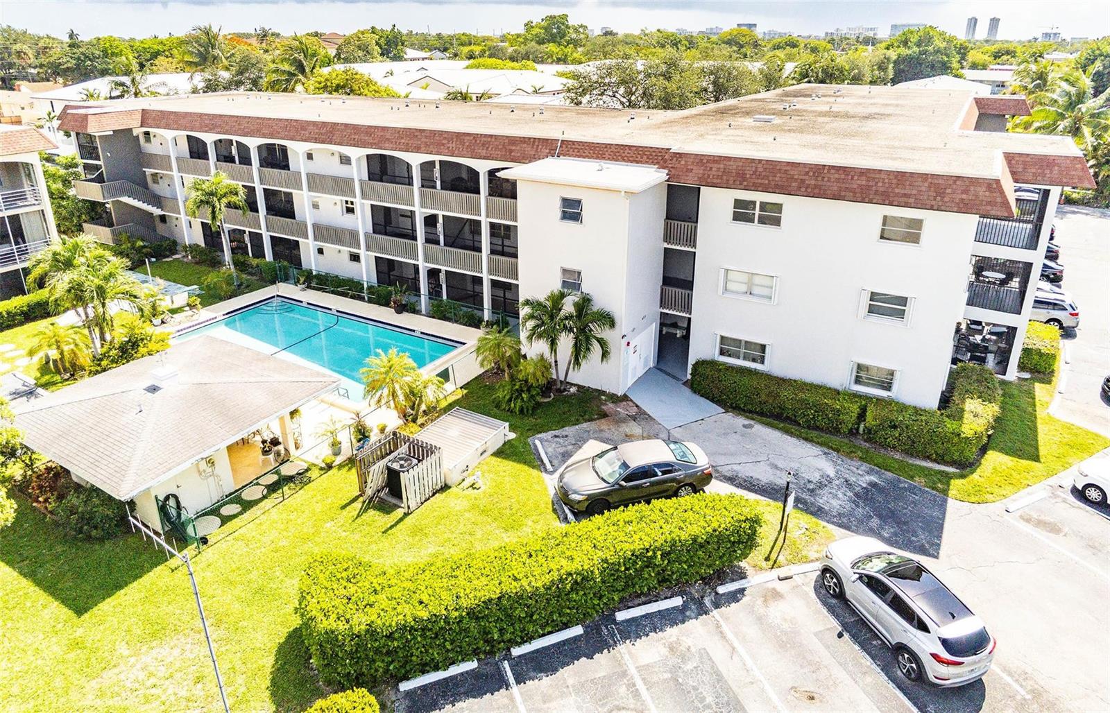 An aerial view of a multi-story apartment building with a swimming pool and parking lot — 651 Pine Drive # 306, Pompano Beach FL 33060, POMPANO BEACH, FL