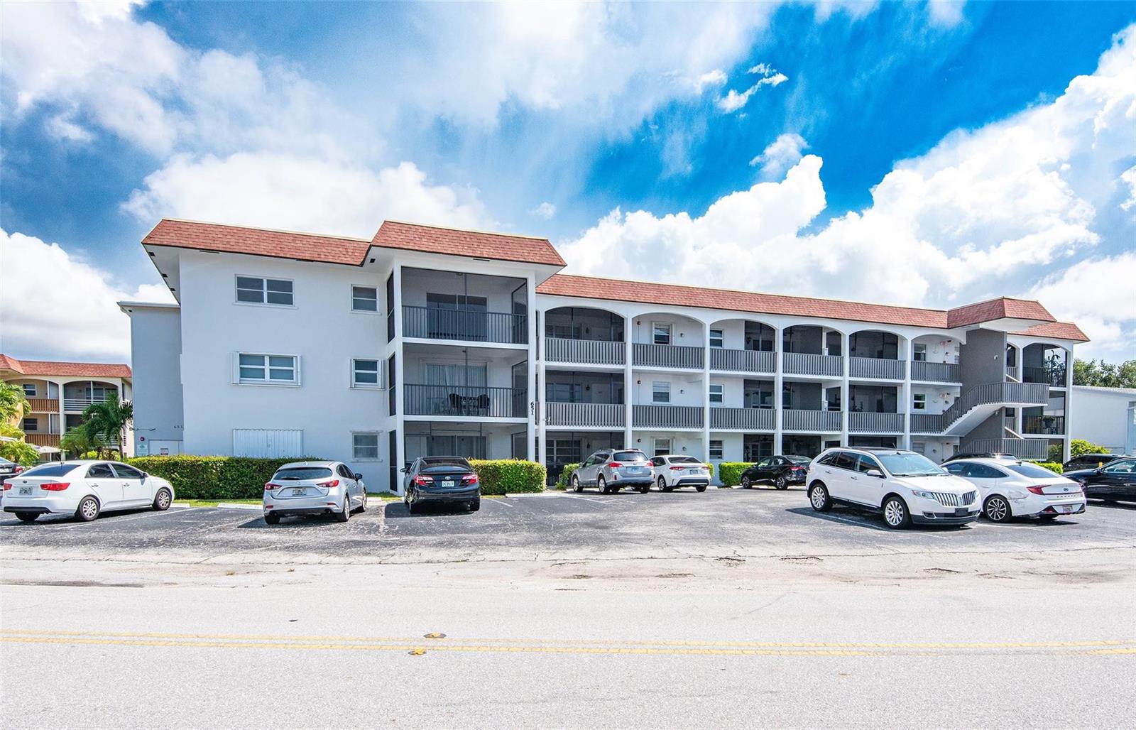 A three-story apartment building with a parking lot in front under a cloudy sky — 651 Pine Drive # 306, Pompano Beach FL 33060, POMPANO BEACH, FL