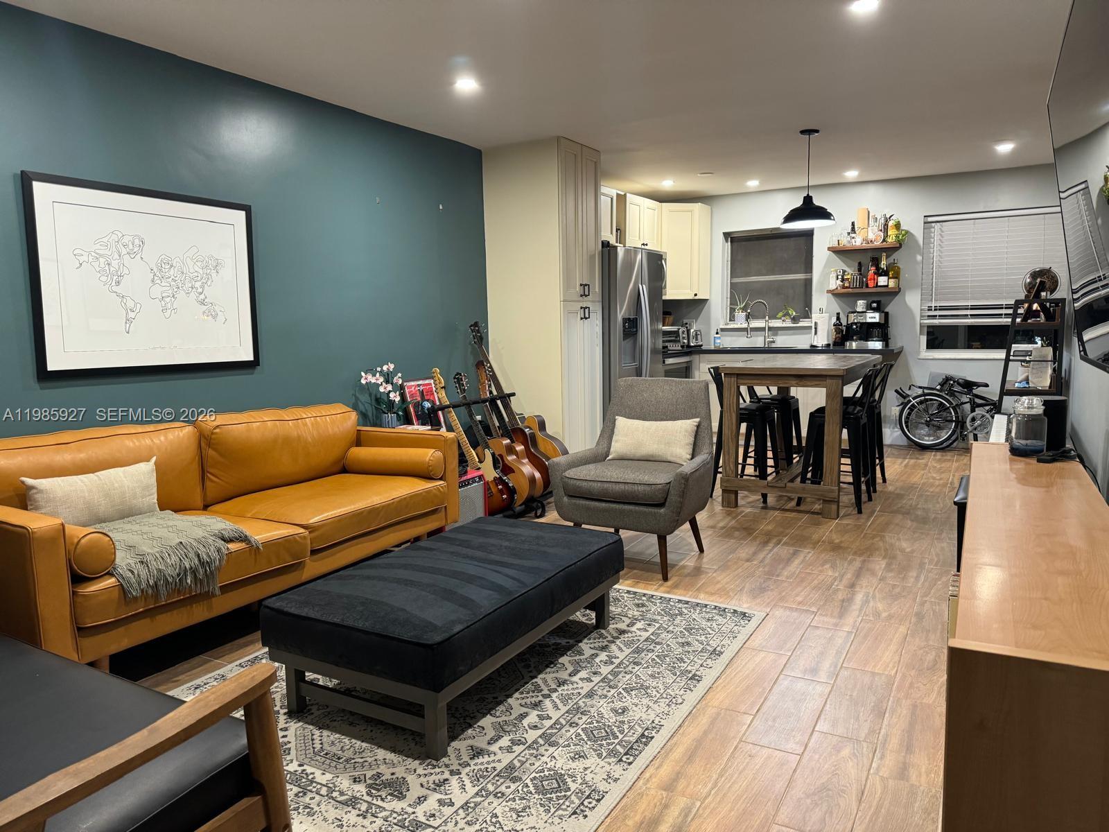 An open-concept living room and kitchen featuring a teal accent wall and leather sofa — 2840 Taylor St # 28, Hollywood FL 33020, HOLLYWOOD, FL